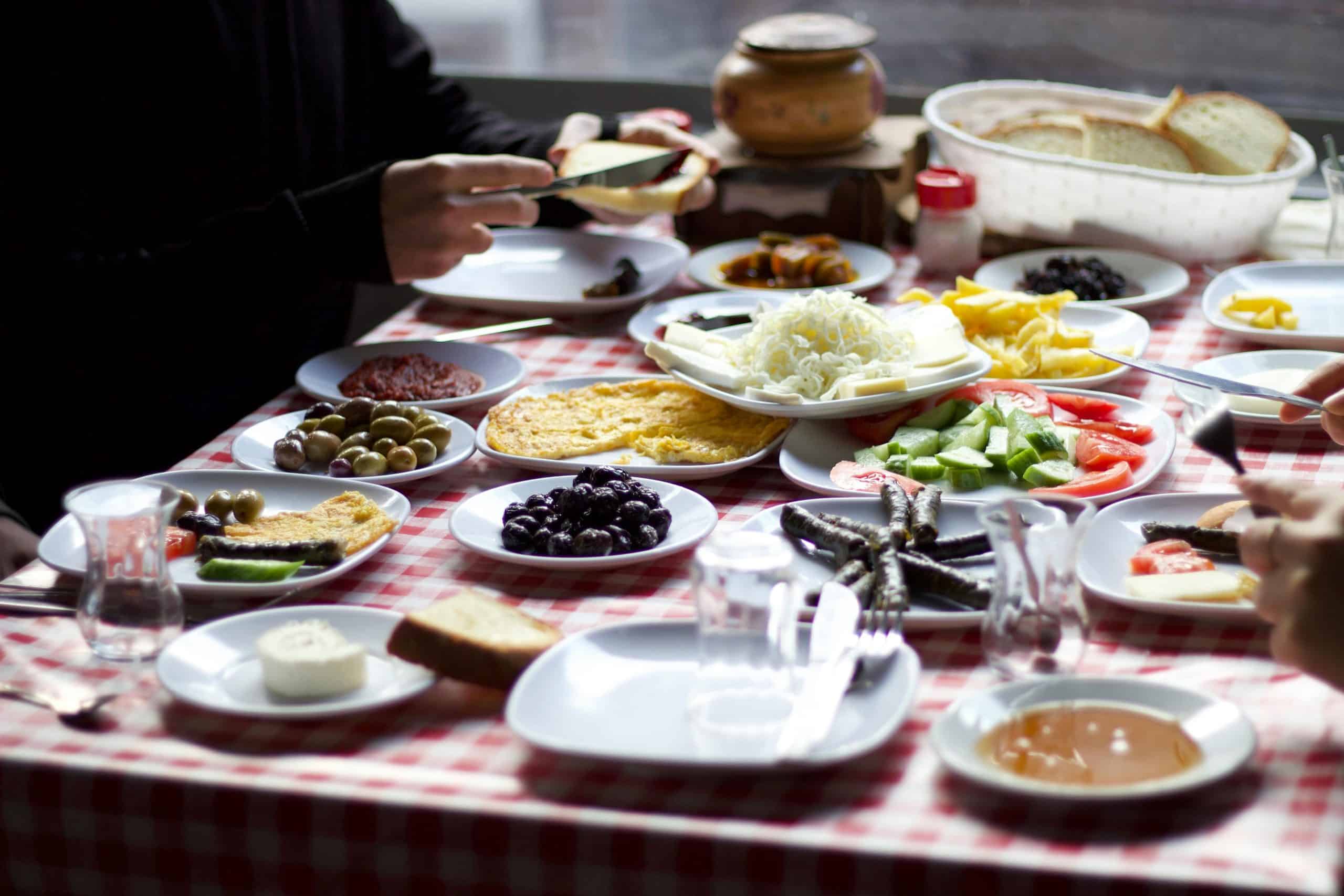 L’art de la découpe : Comment préparer une planche apéritive digne d’un grand chef ? A variety of traditional breakfast dishes served on a red checkered tablecloth indoors, creating a cozy ambiance.